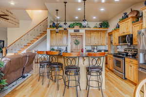 Kitchen featuring stainless steel appliances, light wood-type flooring, a kitchen bar, a center island, and recessed lighting