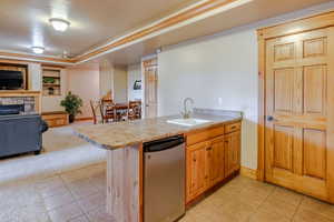 Kitchen featuring a peninsula, light countertops, dishwasher, light tile patterned floors, and ornamental molding