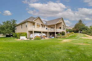 Back of house with stucco siding, a yard, and a deck with mountain view
