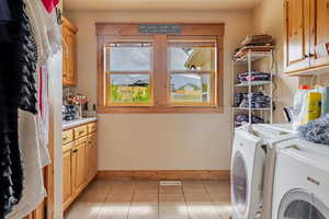 Washroom with cabinet space, light tile patterned floors, and washer and dryer