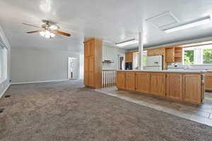 Kitchen with a textured ceiling, light carpet, light countertops, open shelves, and open floor plan