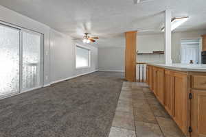 Unfurnished living room with a textured ceiling, a ceiling fan, and light colored carpet