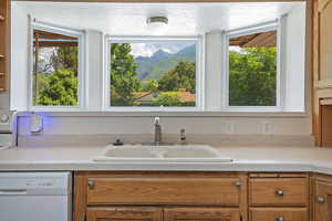 Kitchen with light countertops, white appliances, brown cabinetry, a mountain view, and a textured ceiling