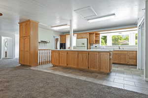 Kitchen with light countertops, a textured ceiling, light carpet, open shelves, and white appliances