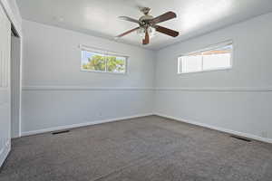 Carpeted empty room featuring a ceiling fan and a textured ceiling