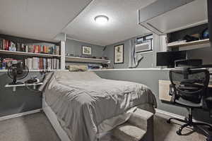Carpeted bedroom with an office area and baseboards