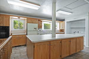 Kitchen with white appliances, light countertops, washer / dryer, plenty of natural light, and a textured ceiling