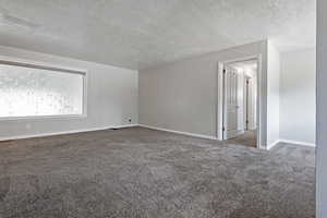 Carpeted spare room with a textured ceiling and baseboards