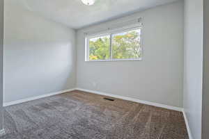 Empty room with carpet and a textured ceiling