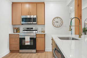 Kitchen featuring stainless steel appliances, light stone countertops, and light wood finished floors