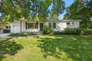 Single story home featuring brick siding, an attached garage, and a front yard