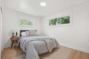 Bedroom featuring wood finished floors, multiple windows, and crown molding