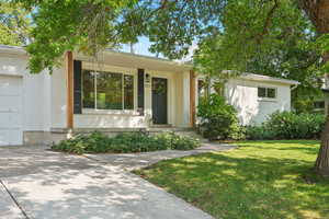 View of front of home with brick siding, a front yard, a garage, and driveway