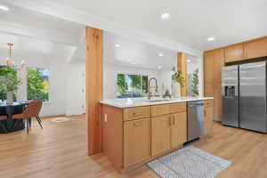 Kitchen with appliances with stainless steel finishes, light wood-style flooring, recessed lighting, light stone countertops, and beamed ceiling
