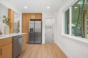 Kitchen featuring appliances with stainless steel finishes, light wood-type flooring, light stone counters, recessed lighting, and healthy amount of natural light