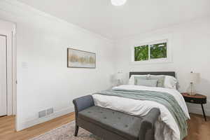 Bedroom featuring wood finished floors and crown molding