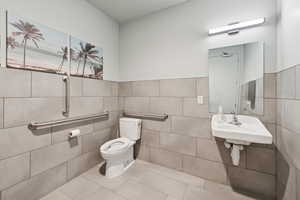 Bathroom with tile walls, tile patterned flooring, and wainscoting