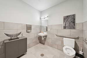 Bathroom with tile walls, tile patterned flooring, and a wainscoted wall
