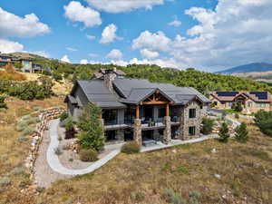 Back of property featuring stone siding, a chimney, a mountain view, and a metal roof