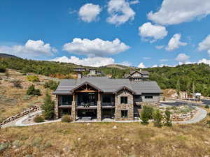 Back of house with stone siding, a metal roof, a patio area, a balcony, and a standing seam roof