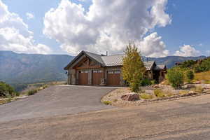 View of front of house with a mountain view, asphalt driveway, a standing seam roof, a metal roof, and stone siding