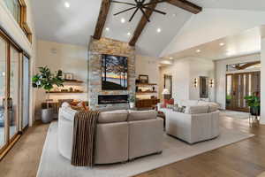 Living area with beamed ceiling, high vaulted ceiling, wood finished floors, a fireplace, and recessed lighting