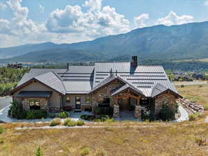 View of front of house with a chimney, a standing seam roof, a metal roof, and stone siding