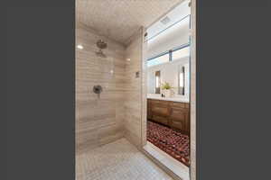 Full bath with a tile shower, light tile patterned floors, and vanity