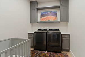Laundry room with washing machine and clothes dryer, cabinet space, and light wood-style floors