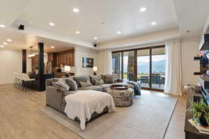 Living room featuring a raised ceiling, recessed lighting, light wood-type flooring, and a mountain view