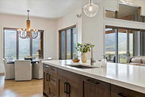 Kitchen featuring dark brown cabinetry, decorative light fixtures, light wood-style flooring, a chandelier, and open floor plan