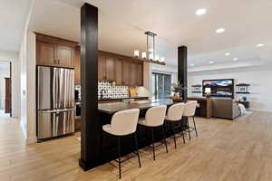 Kitchen with appliances with stainless steel finishes, a kitchen bar, recessed lighting, open floor plan, and hanging light fixtures
