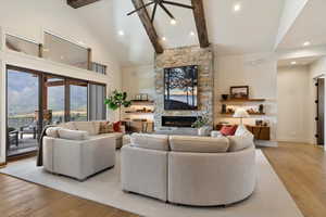 Living room with light wood finished floors, high vaulted ceiling, beam ceiling, a fireplace, and recessed lighting