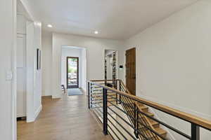 Hall with an upstairs landing, recessed lighting, and light wood-type flooring