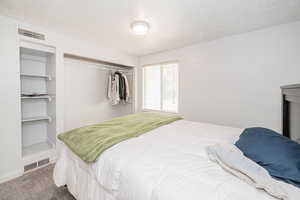 Bedroom featuring a textured ceiling, carpet, and a closet