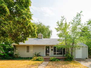 Single story home with a front lawn, a shingled roof, and a porch