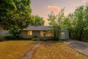 View of front facade featuring a lawn, a porch, and a shingled roof