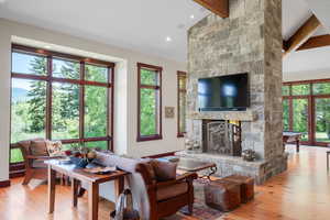 Living area featuring beamed ceiling, hardwood / wood-style floors, a stone fireplace, billiards, and recessed lighting