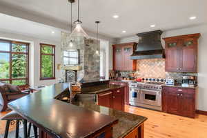 Kitchen featuring glass insert cabinets, healthy amount of natural light, stainless steel appliances, decorative light fixtures, and recessed lighting