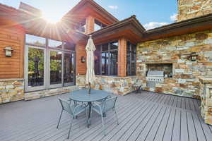 Wooden terrace with outdoor dining space and an outdoor kitchen