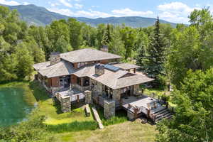Aerial view of property and surrounding area featuring a mountainous background and a forest