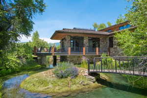 Back of property with stone siding, solar panels, and a water view