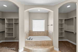 Full bath featuring a walk in closet, recessed lighting, and a bath
