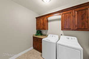Laundry room with cabinet space, separate washer and dryer, and light tile patterned flooring