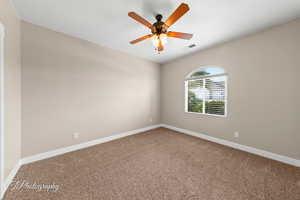 Carpeted spare room with baseboards and a ceiling fan