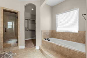 Full bathroom featuring a garden tub, a stall shower, a walk in closet, and tile patterned flooring