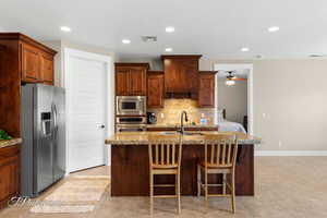 Kitchen featuring recessed lighting, light stone countertops, stainless steel appliances, light tile patterned flooring, and backsplash