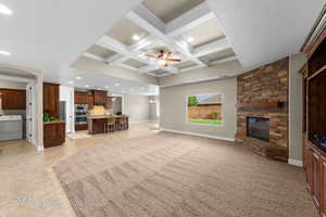Living area with beamed ceiling, coffered ceiling, a ceiling fan, a fireplace, and washer / dryer