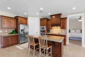 Kitchen with recessed lighting, tasteful backsplash, an island with sink, a breakfast bar, and stainless steel appliances