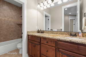 Full bath with double vanity, shower / tub combination, and light tile patterned flooring